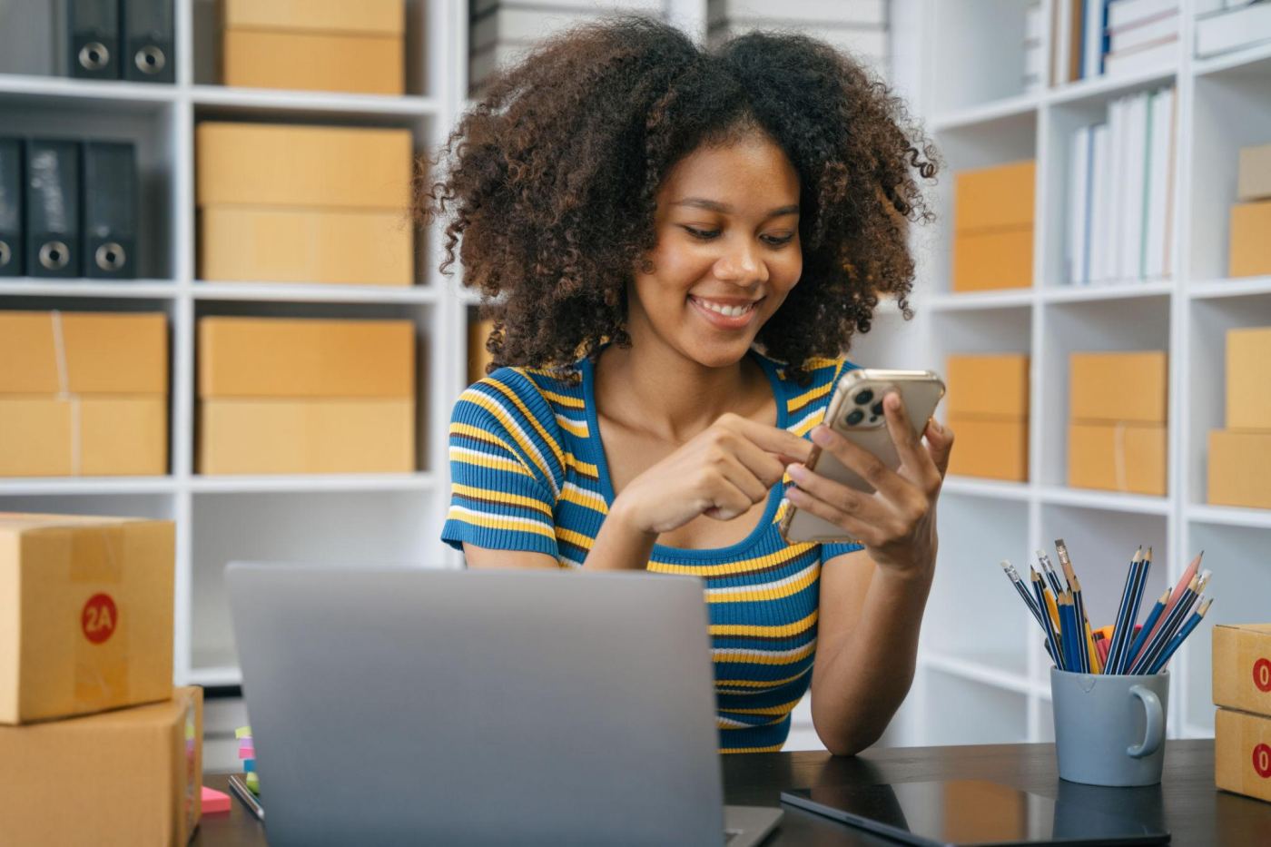 A store owner checking an order on her phone among parcels